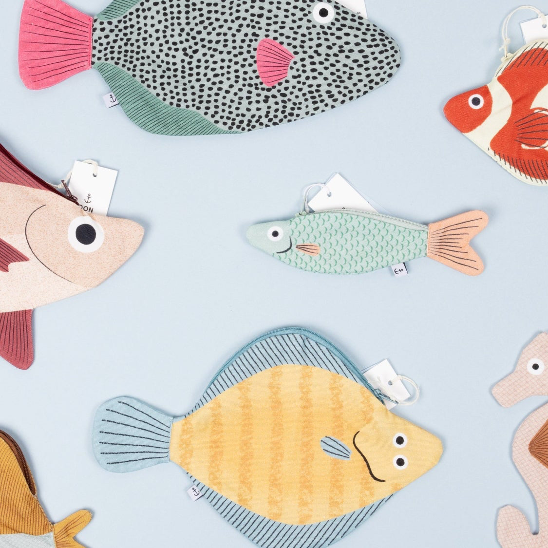 Various Don Fisher fish pouches and cases on a light blue background.