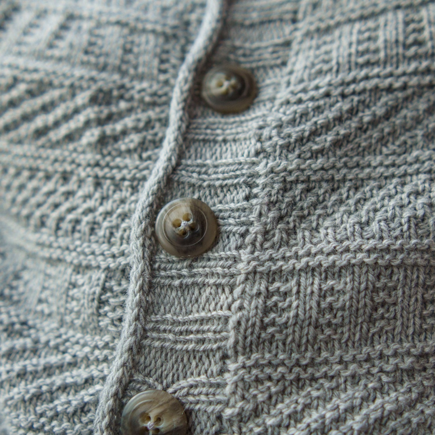 This image shows a detail of a beautifully knitted sample of the Dustland Cardigan in grey.