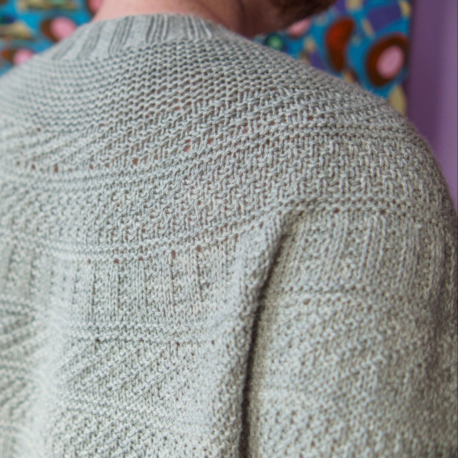 This image shows Stephen West wearing a beautifully knitted sample of the Dustland Cardigan in grey.
