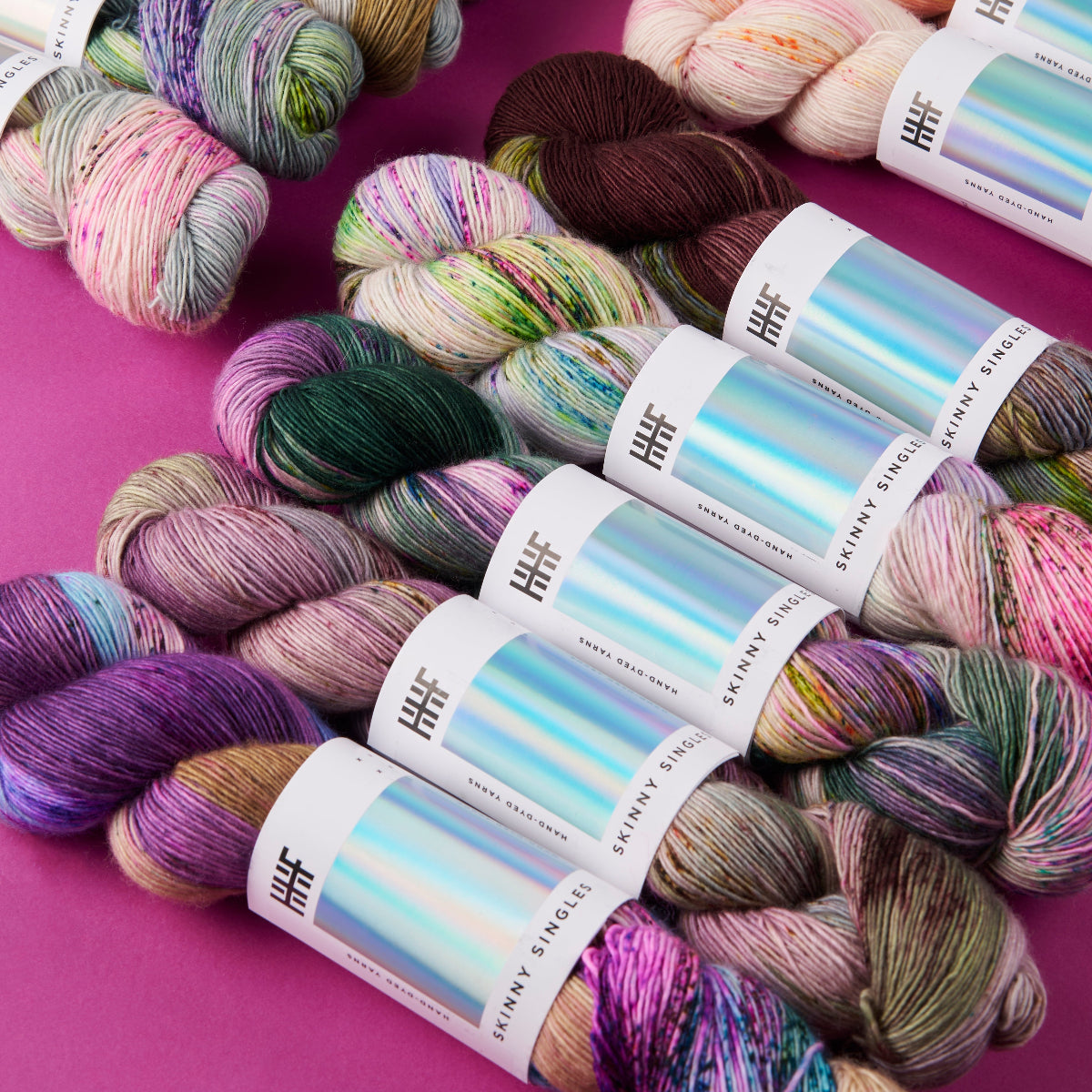 Colorful yarn skeins with labels on a pink background