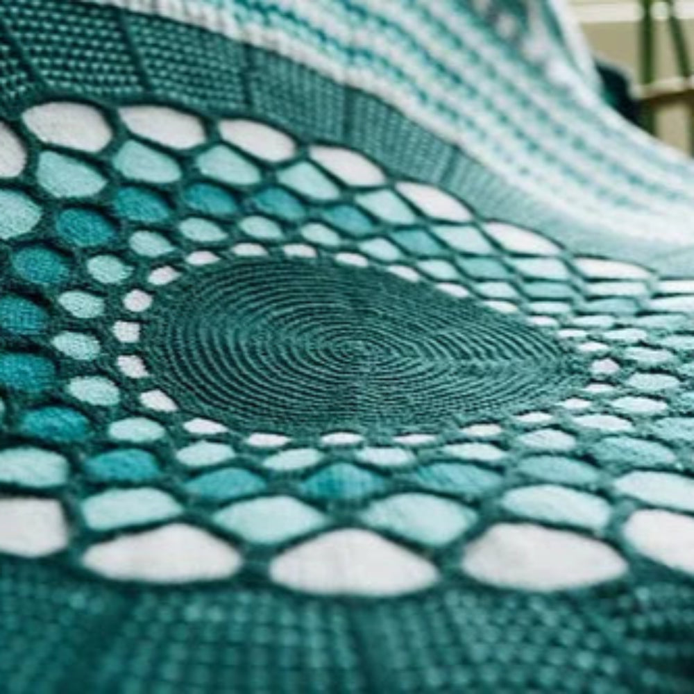 This image shows a detail of a beautifully knitted sample of the Slipstravaganza Blanket in cool blue and turquoise tones.