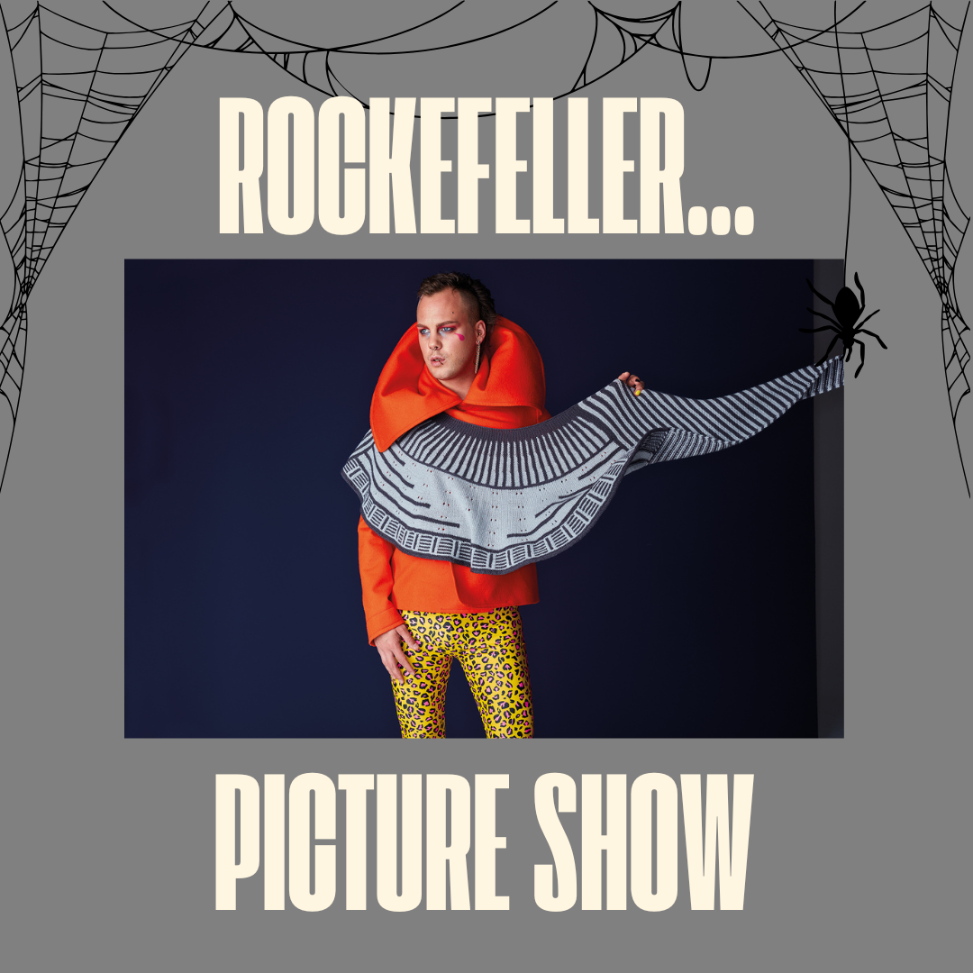 Person wearing a orange jacket with a navy and grey shawl draped across their body with bright yellow leopard print trousers. Text reads Rockefeller picture show.