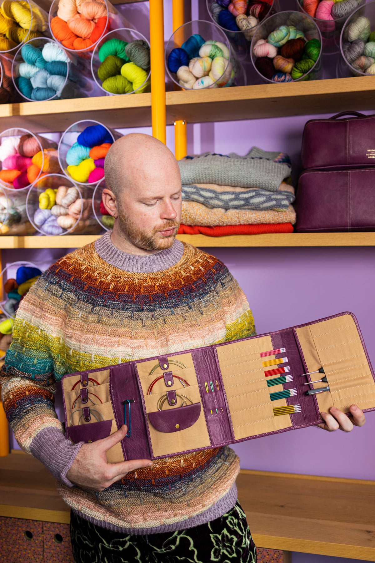 This image shows Stephen West wearing Project 14 - Aubergine, filled with needles. The bag is part of a collaboration between Re:Designed and Westknits. 