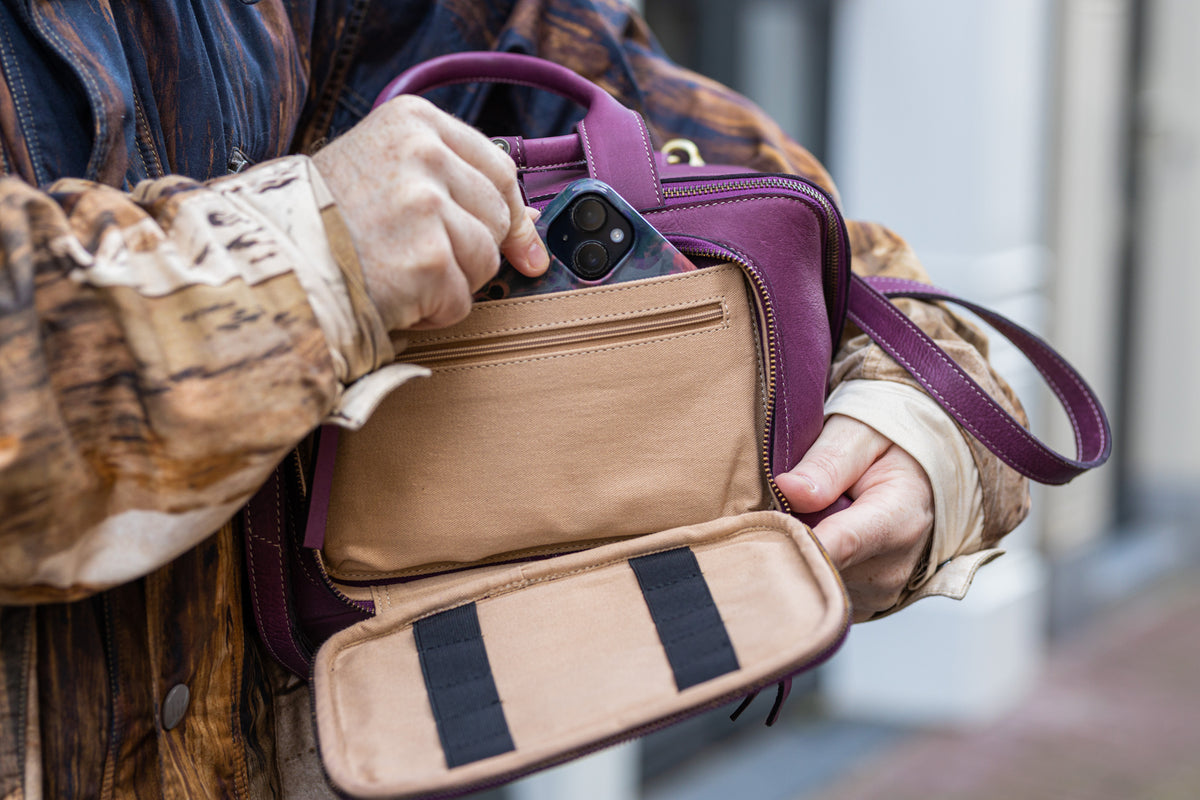 This image shows Project 39 - Aubergine. The bag is part of a collaboration between Re:Designed and Westknits. Stephen West is holding a phone from the bag.