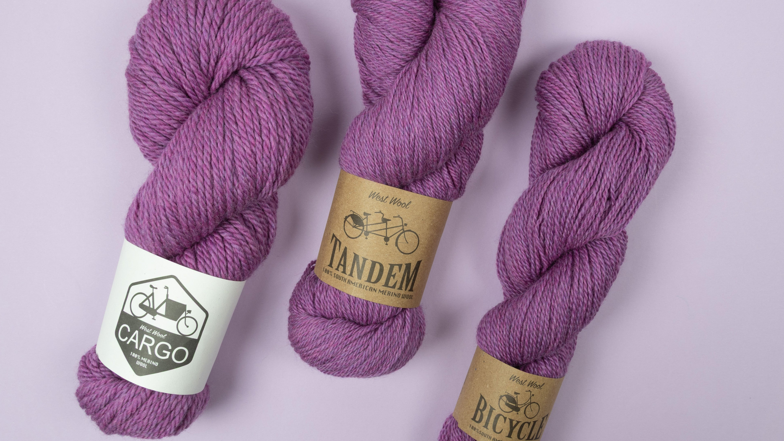 Three skeins of purple yarn with labels on a light purple background
