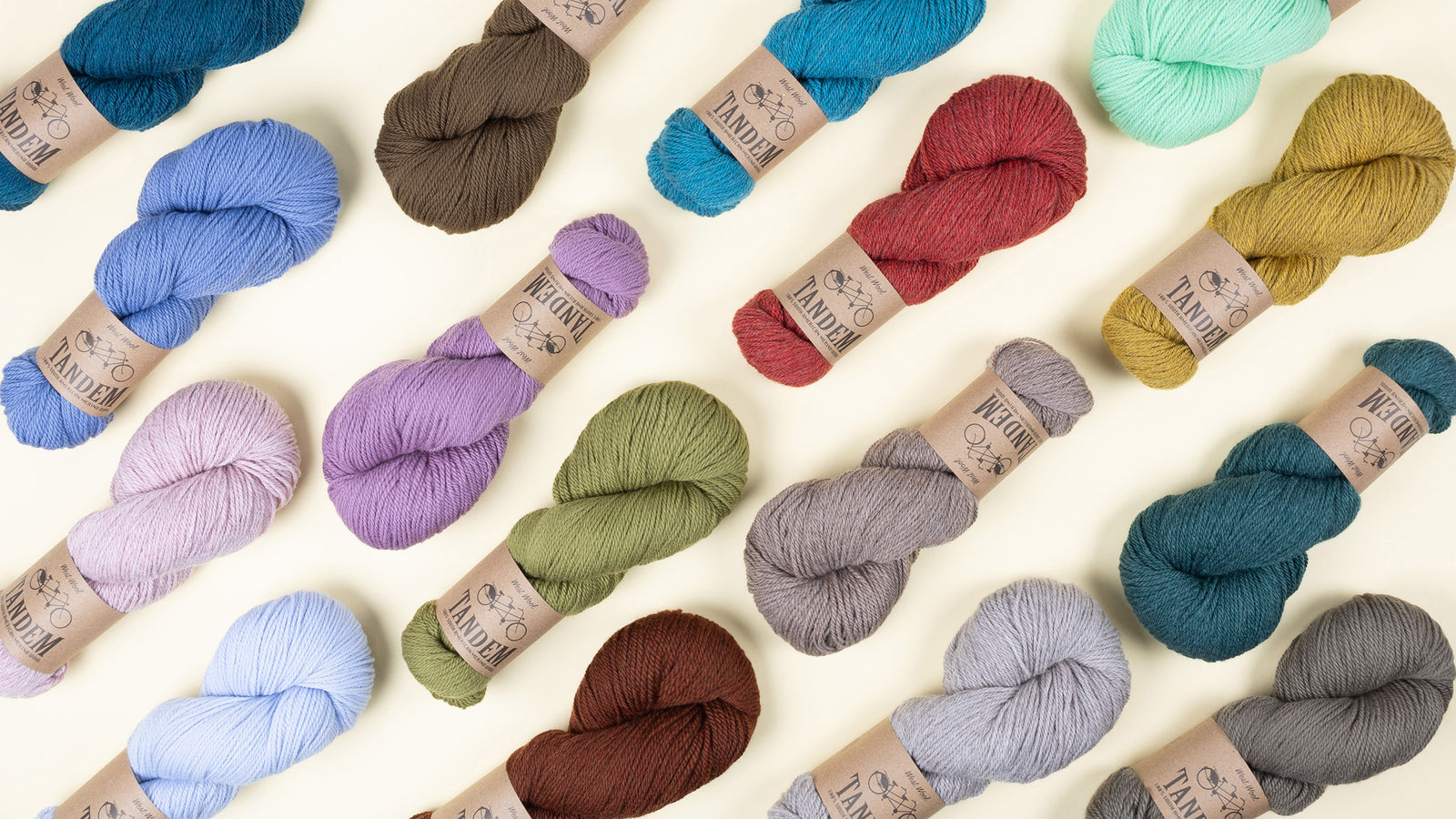 This image shows the variety of new colours of Tandem from West Wool on a pastel yellow background. The colours include brown, coral, orange, blue and green. 