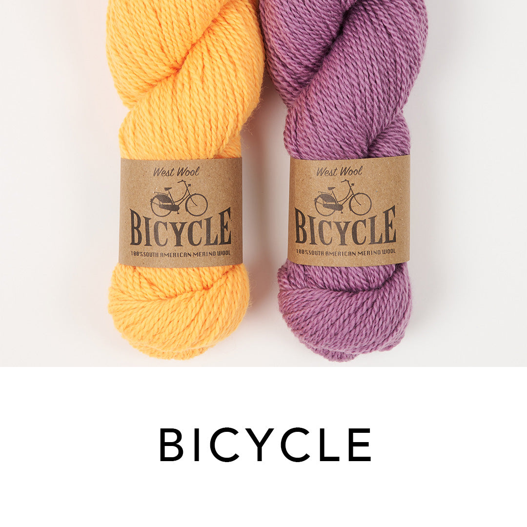 This image shows 2 skeins of West Wool Bicycle in orange and purple, on a white background. 