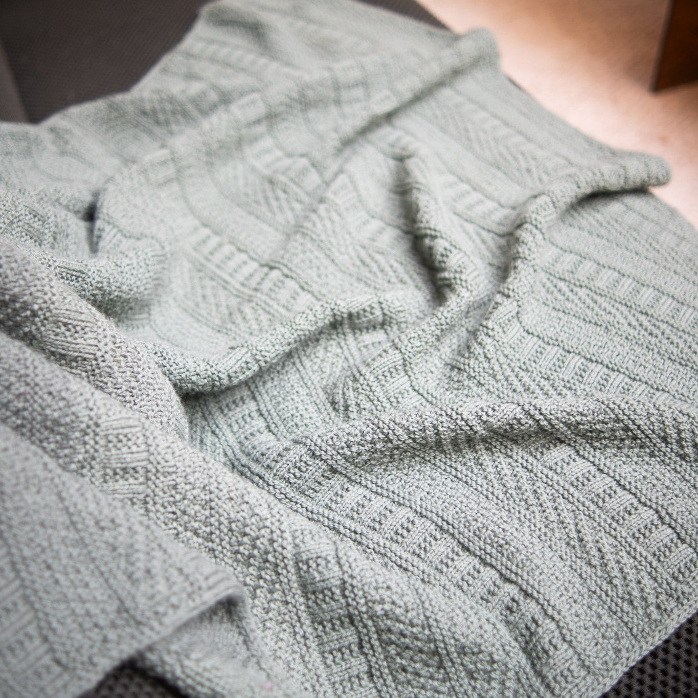This image shows a detail of a beautifully knitted sample of the Dustland Blanket by Westknits in grey yarn.