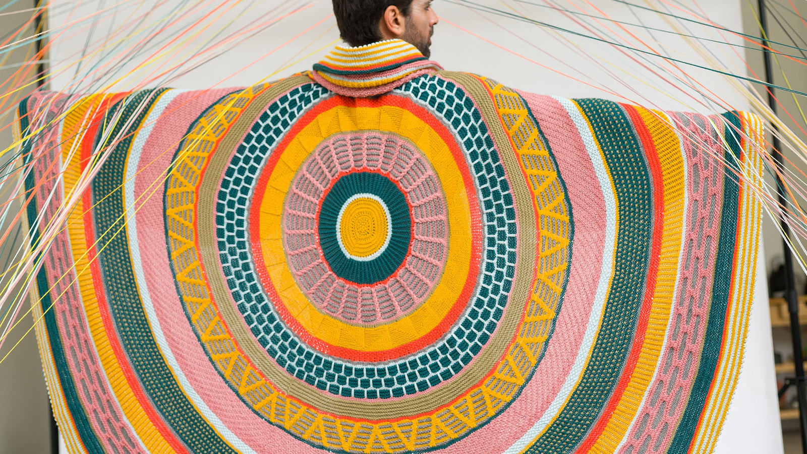 This image shows a beautifully knitted sample of the Fantastitch Blanket by Westknits in various colours, including green, pink, yellow, and coral tones. 