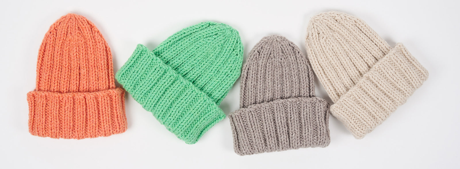 This image shows 4 sample of knitted hats in coral, green, and neutral colours on a white background. 