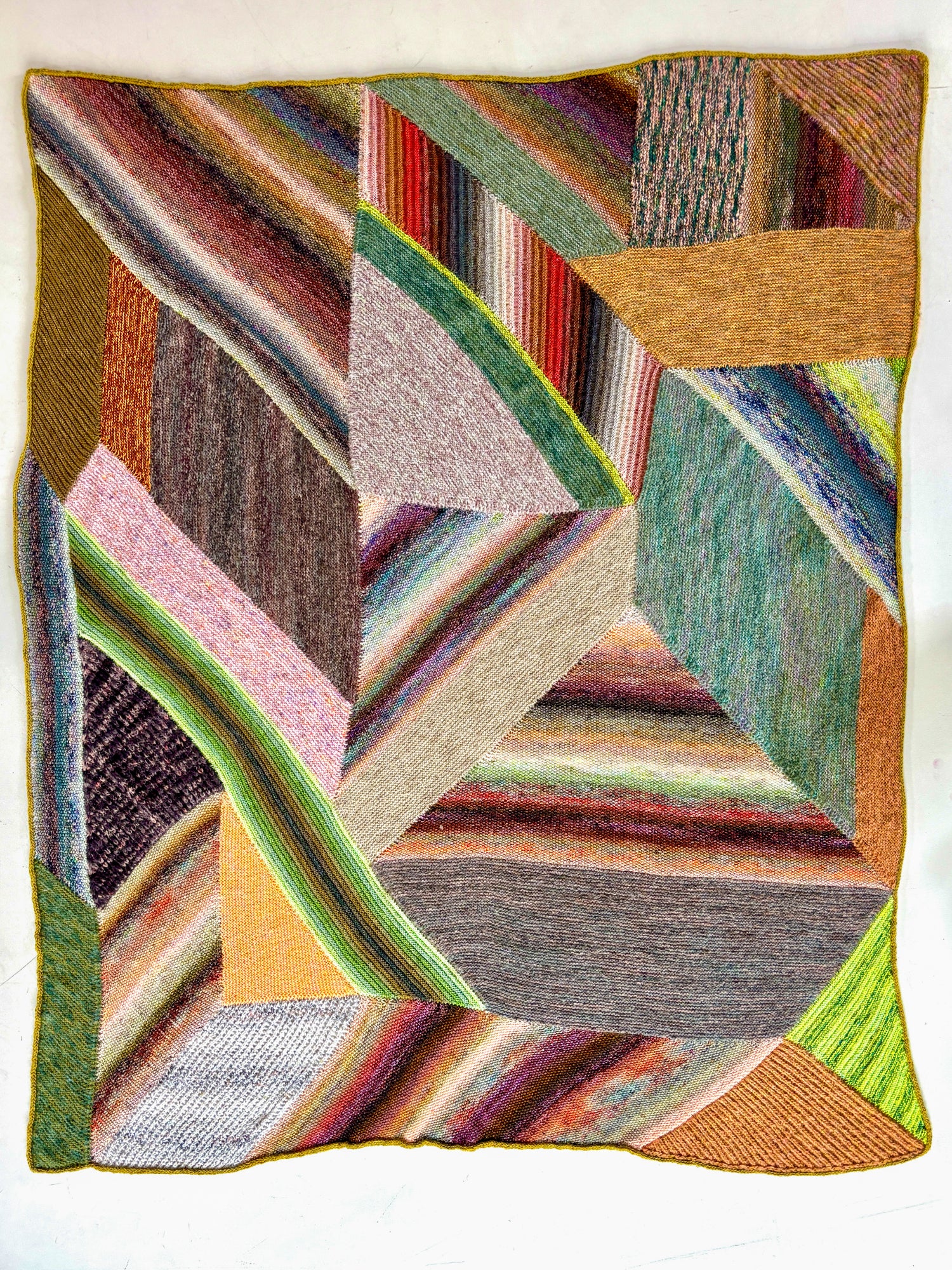 This image shows a sample of the beautifully knitted Marled Magic Blanket from Westknits. The blanket is knitted with various colours and has a patchwork layout. 