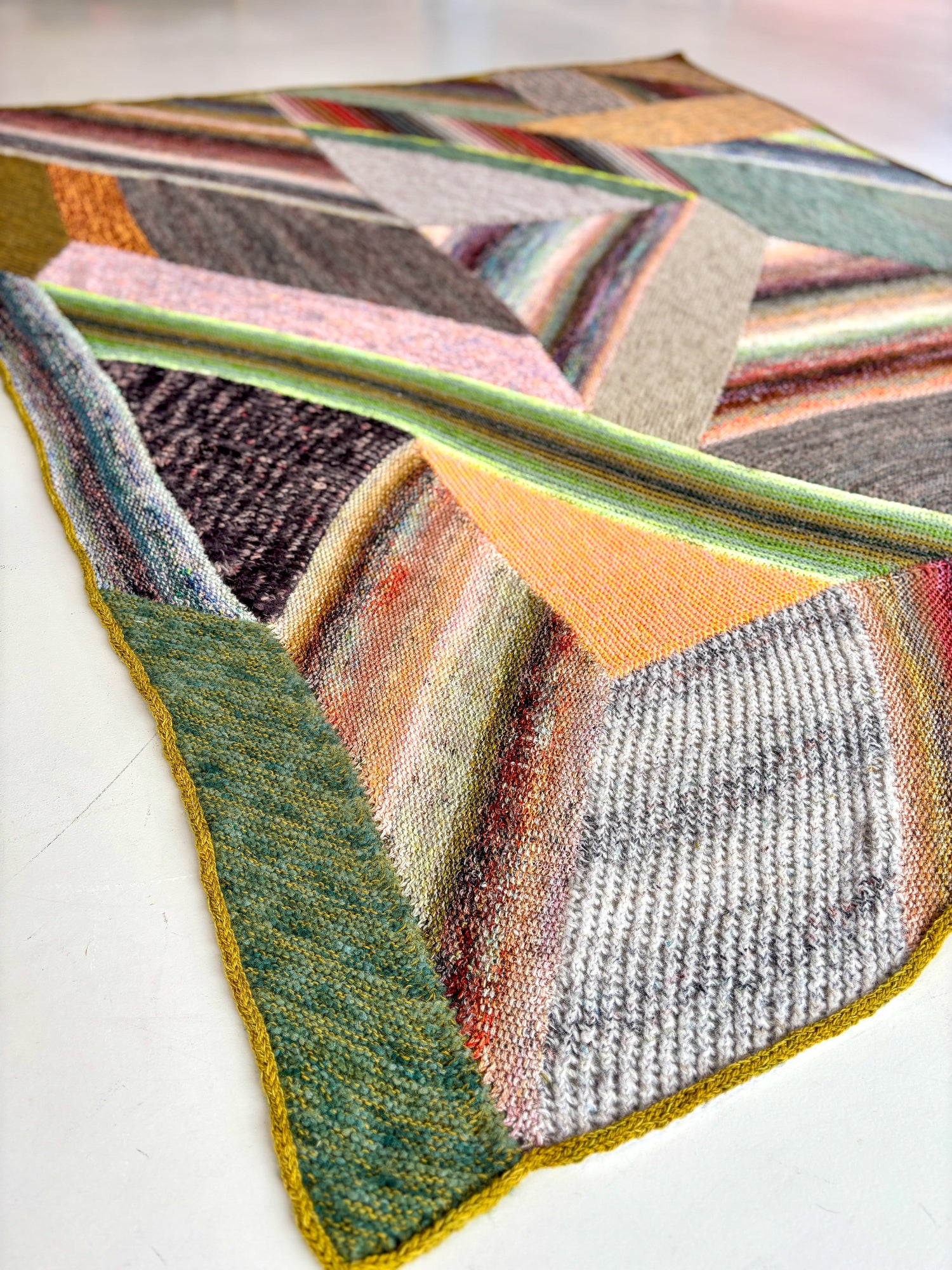 This image shows a sample of the beautifully knitted Marled Magic Blanket from Westknits. The blanket is knitted with various colours and has a patchwork layout. 