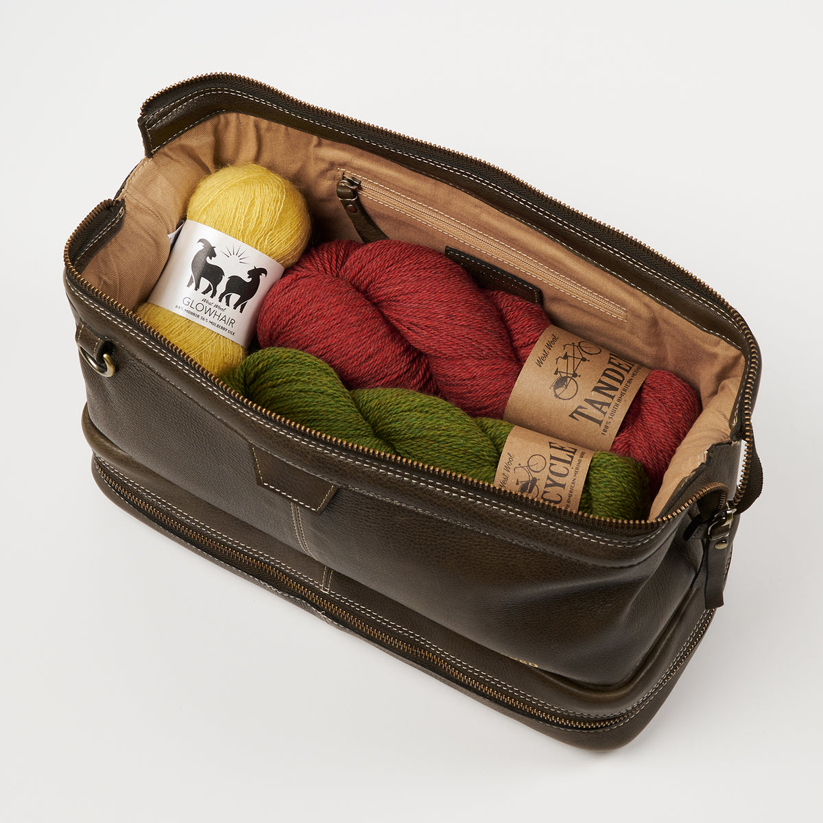 This image shows a dark green bag from Re:Designed collaboration filled with West Wool yarn. 