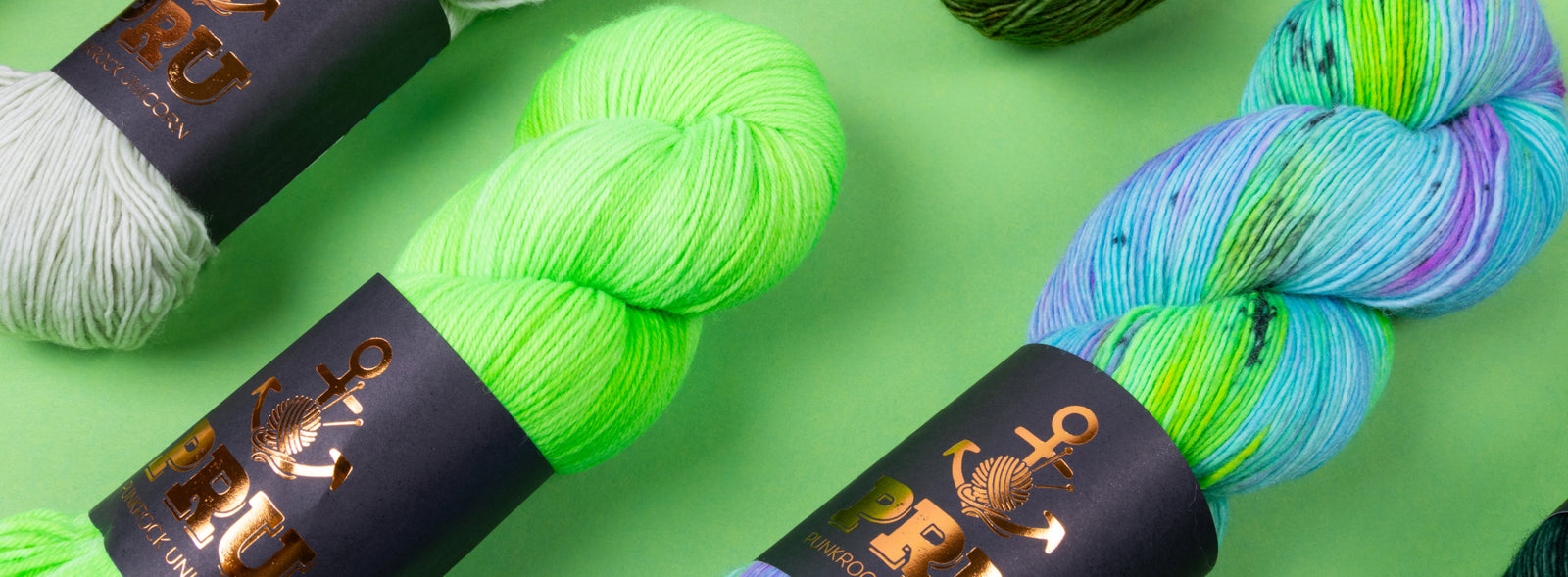 This image shows various skeins of PRU in various bright colours on a green background. 