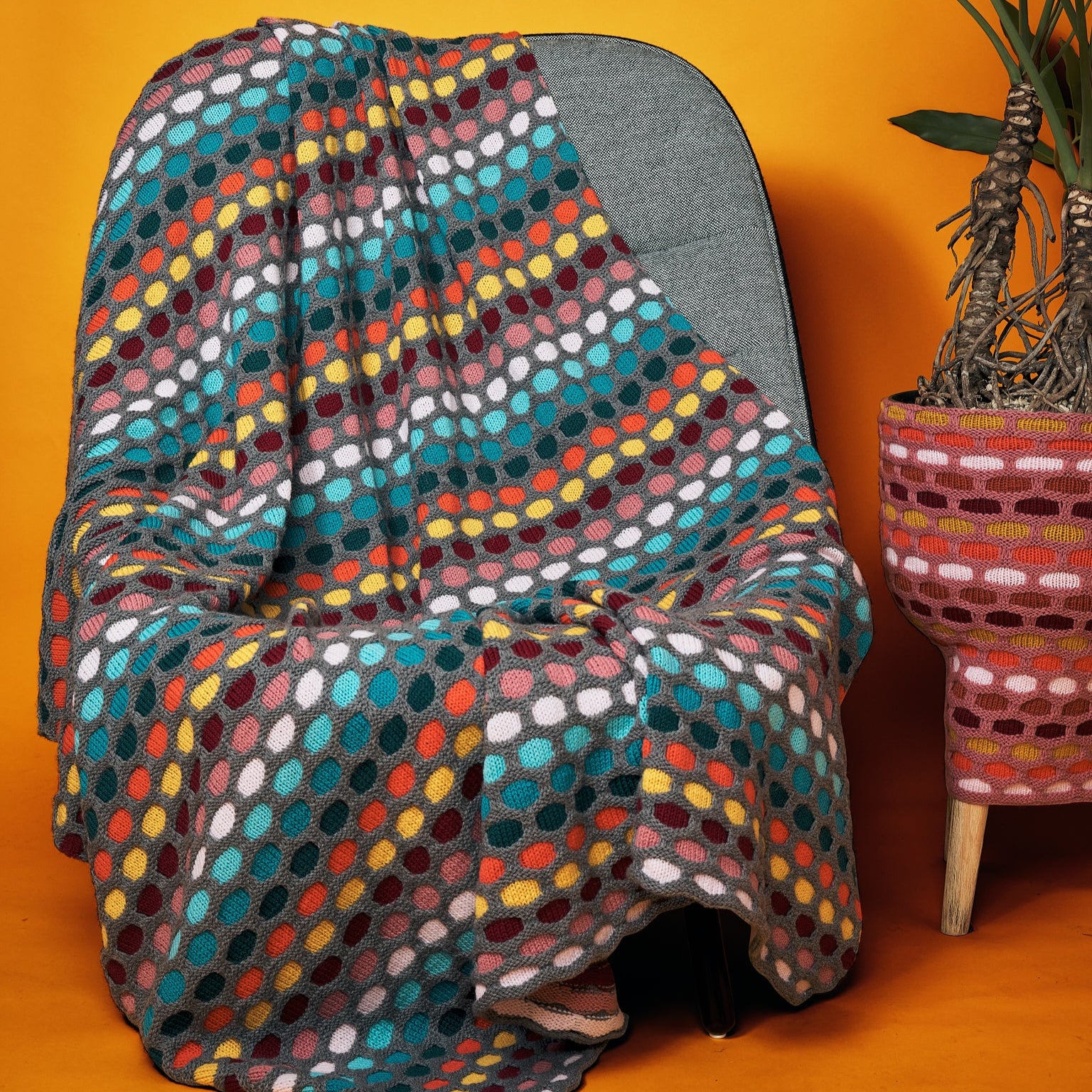 This image shows a knitted sample of the Painting Honeycombs Blanket by Westknits in various colours, including grey, yellow, orange, blue. 