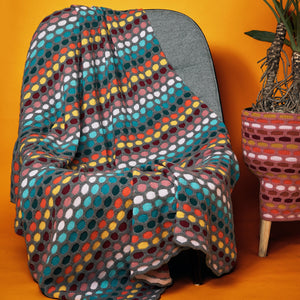 This image shows a knitted sample of the Painting Honeycombs Blanket by Westknits in various colours, including grey, yellow, orange, blue. 