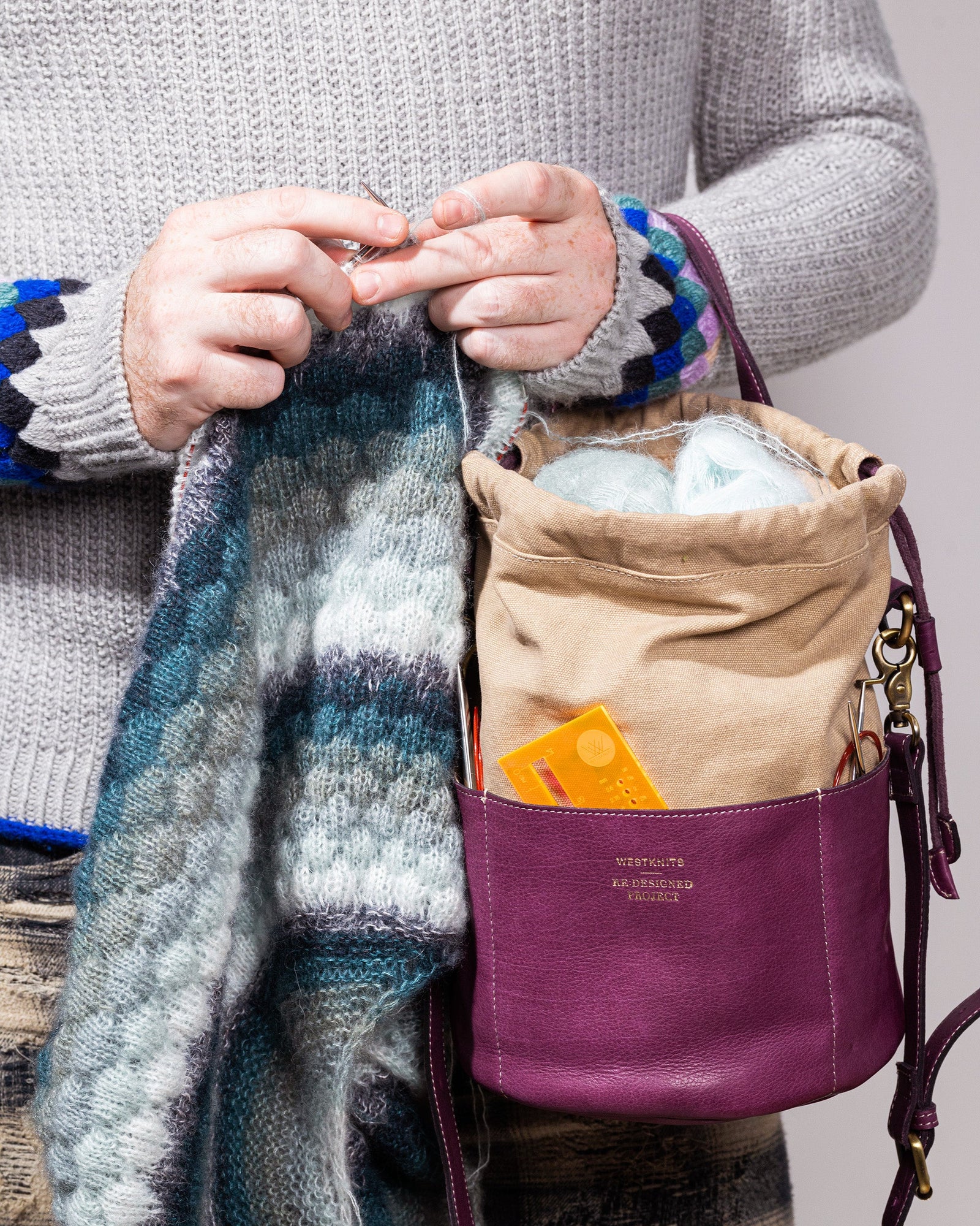 This image shows Stephen West working on a project. The yarn of the project is stored in Project 61 - Aubergine, which is part of the collaboration between Westknits and Re:Designed. 