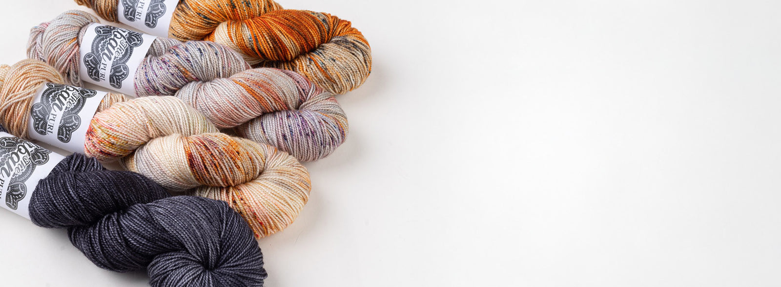 This image shows 4 skeins of Lux High Twist from The Urban Purl in grey, orange, and purple tones on a white background.