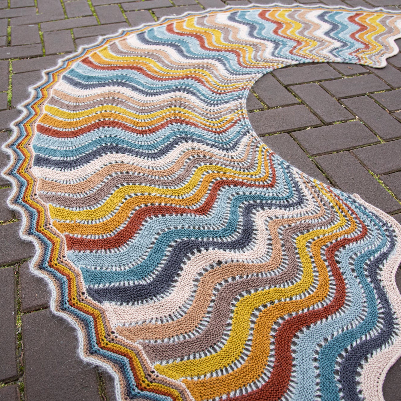 This image shows a beautifully knitted multicolour sample of the Replendence Shawl by Westknits. 