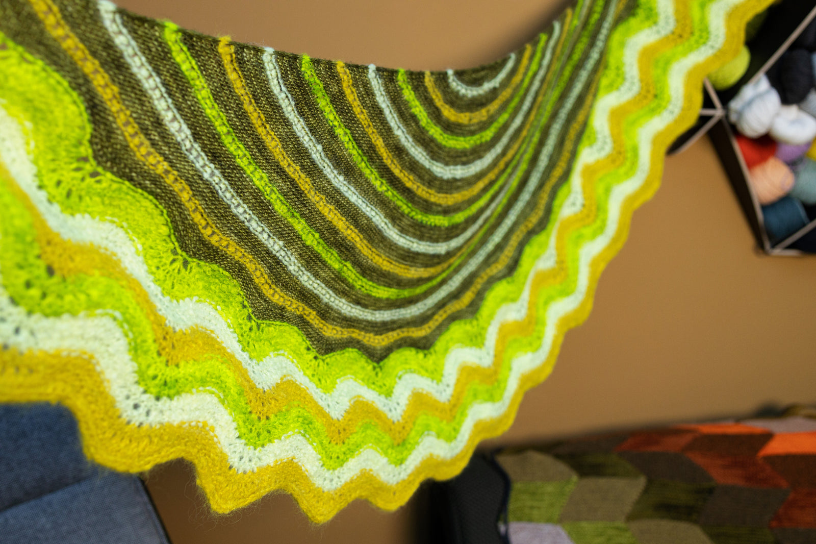 This image shows a  beautifully knitted sample of the Suri Shimmy Shawl in green and yellow gradients. 