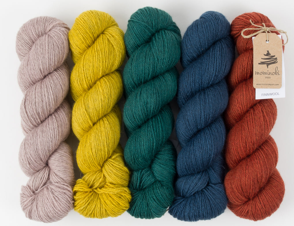 Skeins of Mominoki yarn in gradient colours on a white background