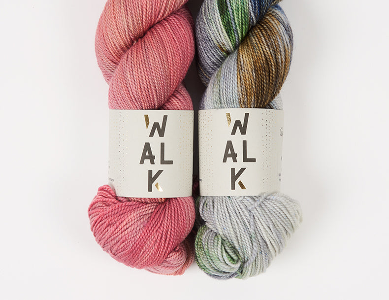 This image shows two skeins of Walk Collection Merino Sport in pink and a variegated brown and grey colour. It stands on a white background. 