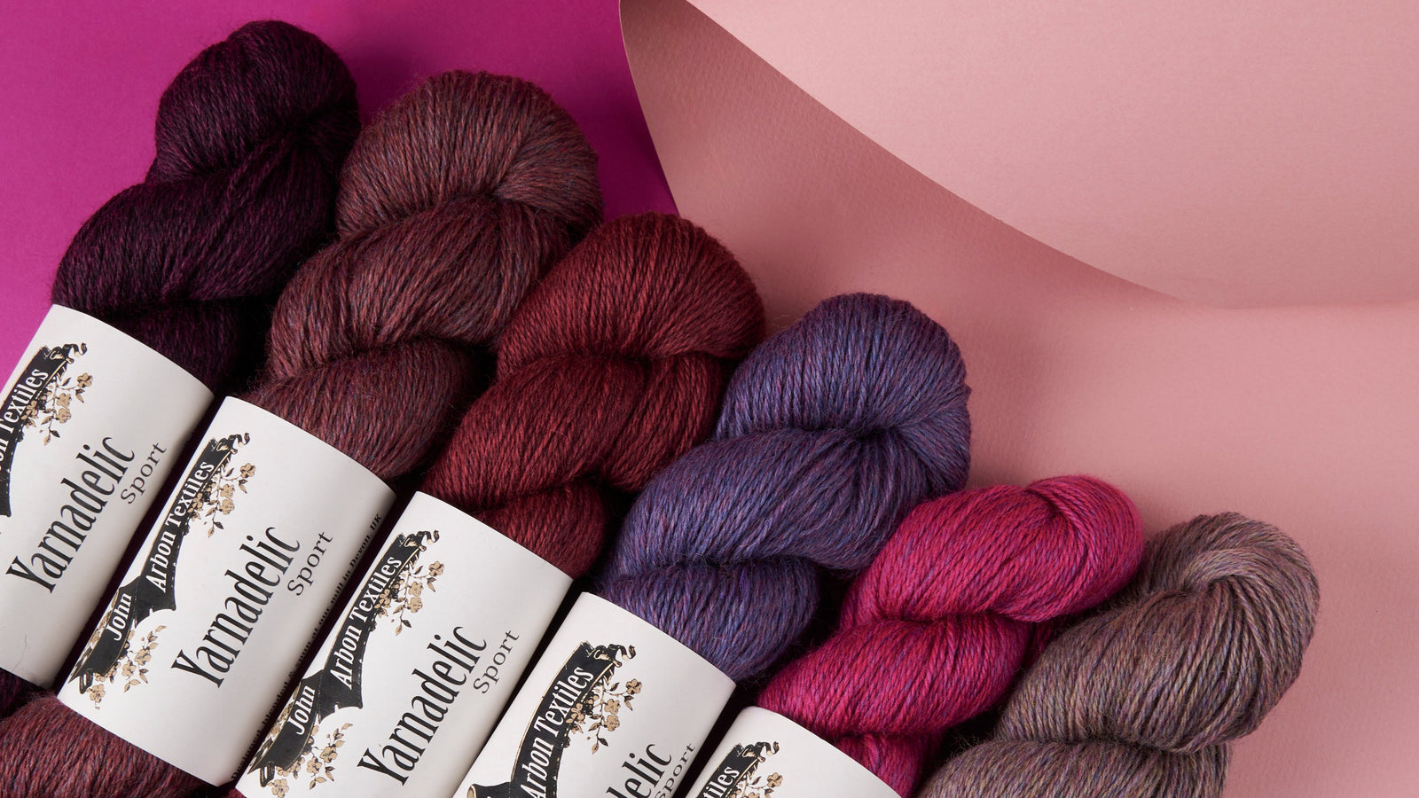 Yarn skeins with labels on a pink and purple background