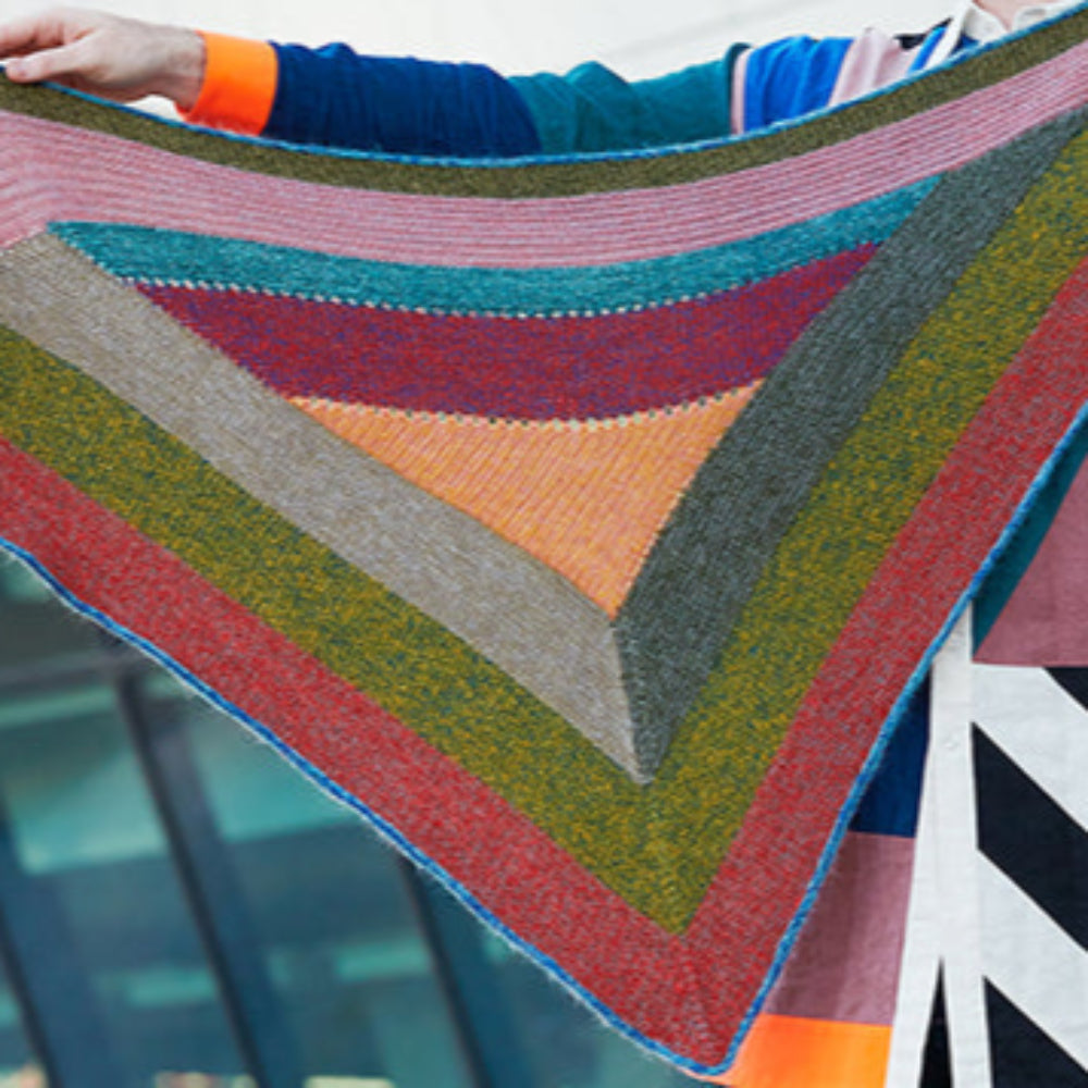 This image shows Stephen West wearing a beautifully knitted sample of the Mohair Mixer Shawl by Westknits in various colours. 