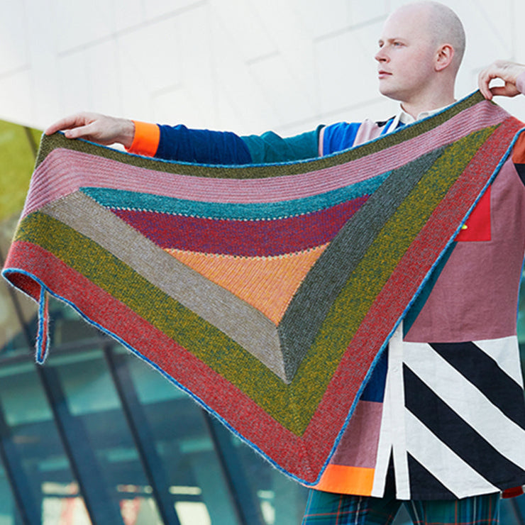 This image shows Stephen West wearing a beautifully knitted sample of the Mohair Mixer Shawl by Westknits in various colours. 